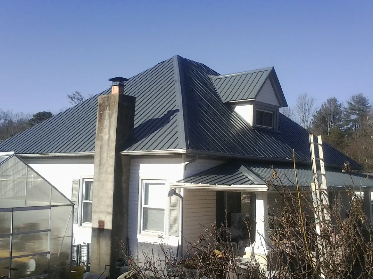 Dark blue standing seam metal roof on a white farmhouse with dormer — Slate & Tile Roof Repair by Roofing Brothers in Foothill Ranch