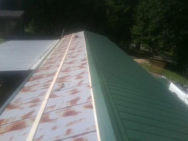 Old rusted panels beside newly installed green metal roofing — Wind Damage Roof Repair by Roofing Brothers in Foothill Ranch