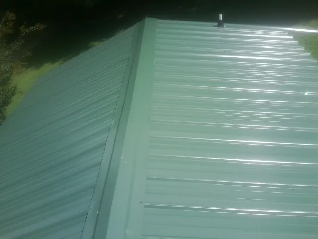 New green metal panels meeting at the ridge of a roof — Flat Roof Repair work by our crew in Foothill Ranch